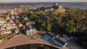 An aerial view of a coastal town with a prominent castle, a large swimming pool, and a marina. - Marstrands Kurhotell  (Marstrand)