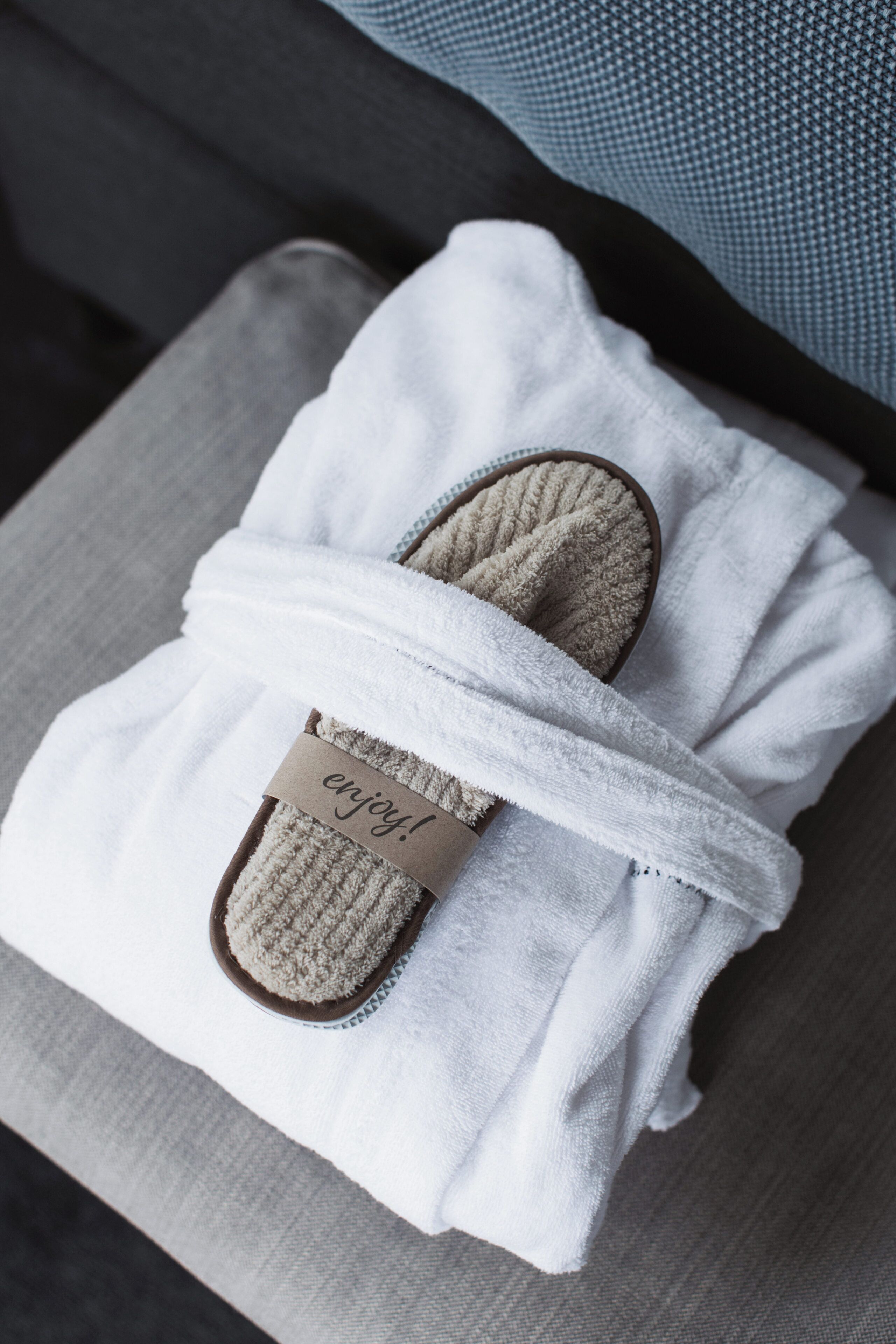 A pair of slippers wrapped in a white towel with a tag that says 'enjoy!'