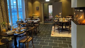 A cozy dining area with a fireplace, wooden furniture, and a view of the sea through large windows. - Marstrands Kurhotell  (Marstrand)