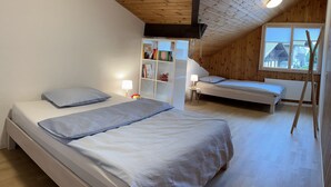 Une chambre avec deux lits, un plafond en bois, des murs blancs et une fenêtre donnant sur un paysage agréable.