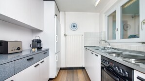 Una cocina moderna con armarios blancos, encimera negra, estufa y un reloj en la pared.