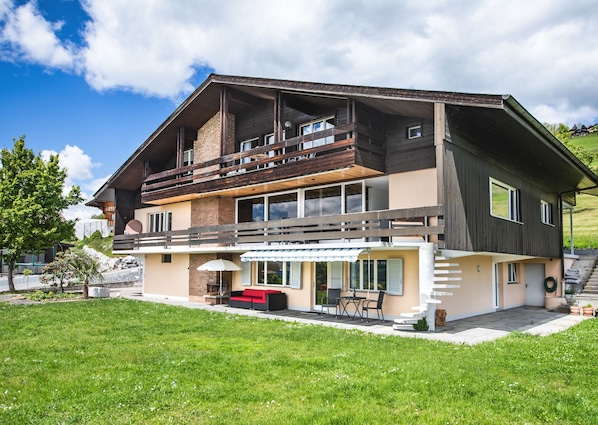 A two-story house with a balcony, a patio with outdoor furniture, and a well-maintained lawn. - "little lizard" An apartment for two (Aeschlen ob Gunten)