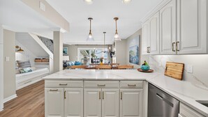 A kitchen with white cabinets, a large island, and pendant lighting. - OCEANFRONT Views, Community Pool, Modern, Ideal Wild Dunes Location! (Isle Of Palms)