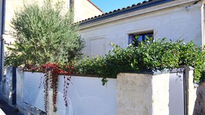 A building with a white exterior, a tiled roof, and a window with blue shutters.
