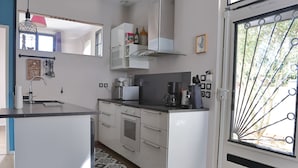 A compact kitchen with white cabinets, a built-in oven, and a coffee maker.
