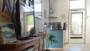 A spacious room with a wooden floor, a kitchen area with a blue countertop, and a bookshelf filled with books.