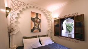Un dormitorio con cama, diseños decorativos en la pared, una ventana con vistas y una obra de arte colgada en la pared.