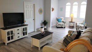 Un salon comprenant un téléviseur, un canapé, des fauteuils et une table basse.