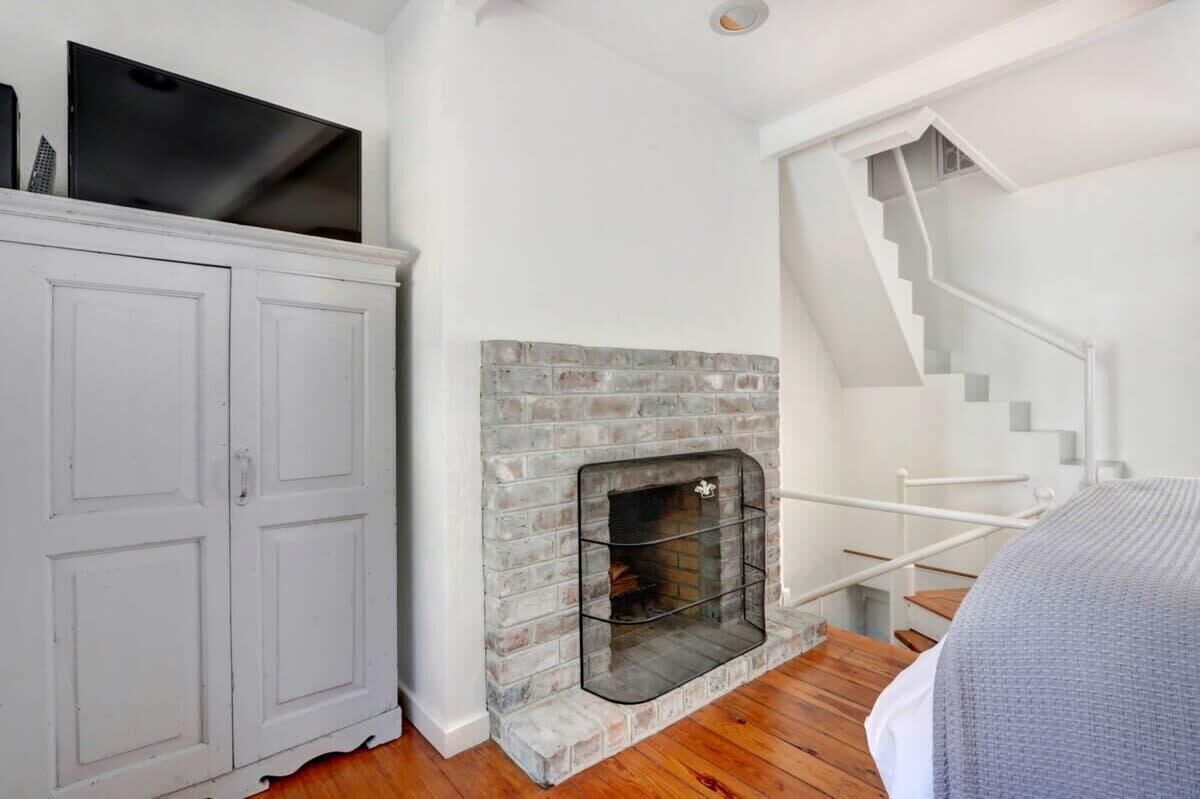 A room with a fireplace, a staircase, and a wardrobe.