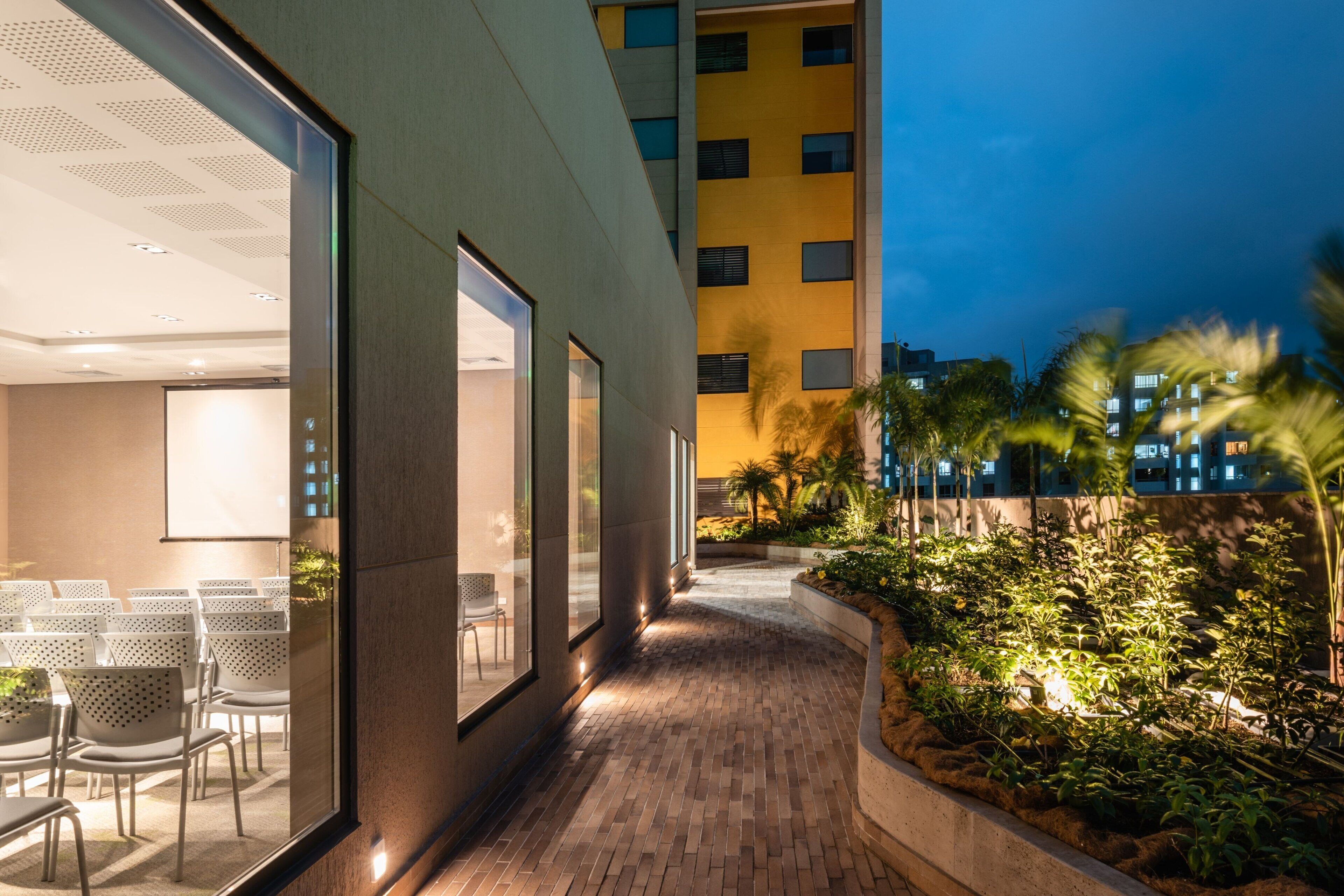Un edificio moderno con un sendero de ladrillo que lleva a una zona de estar con sillas y una mesa.