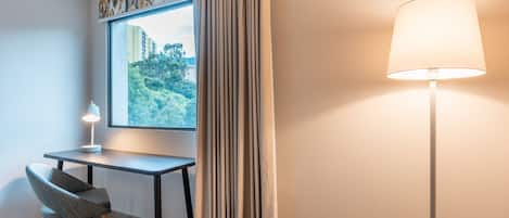 Una habitación de hotel moderna con escritorio, silla y lámpara de pie.
