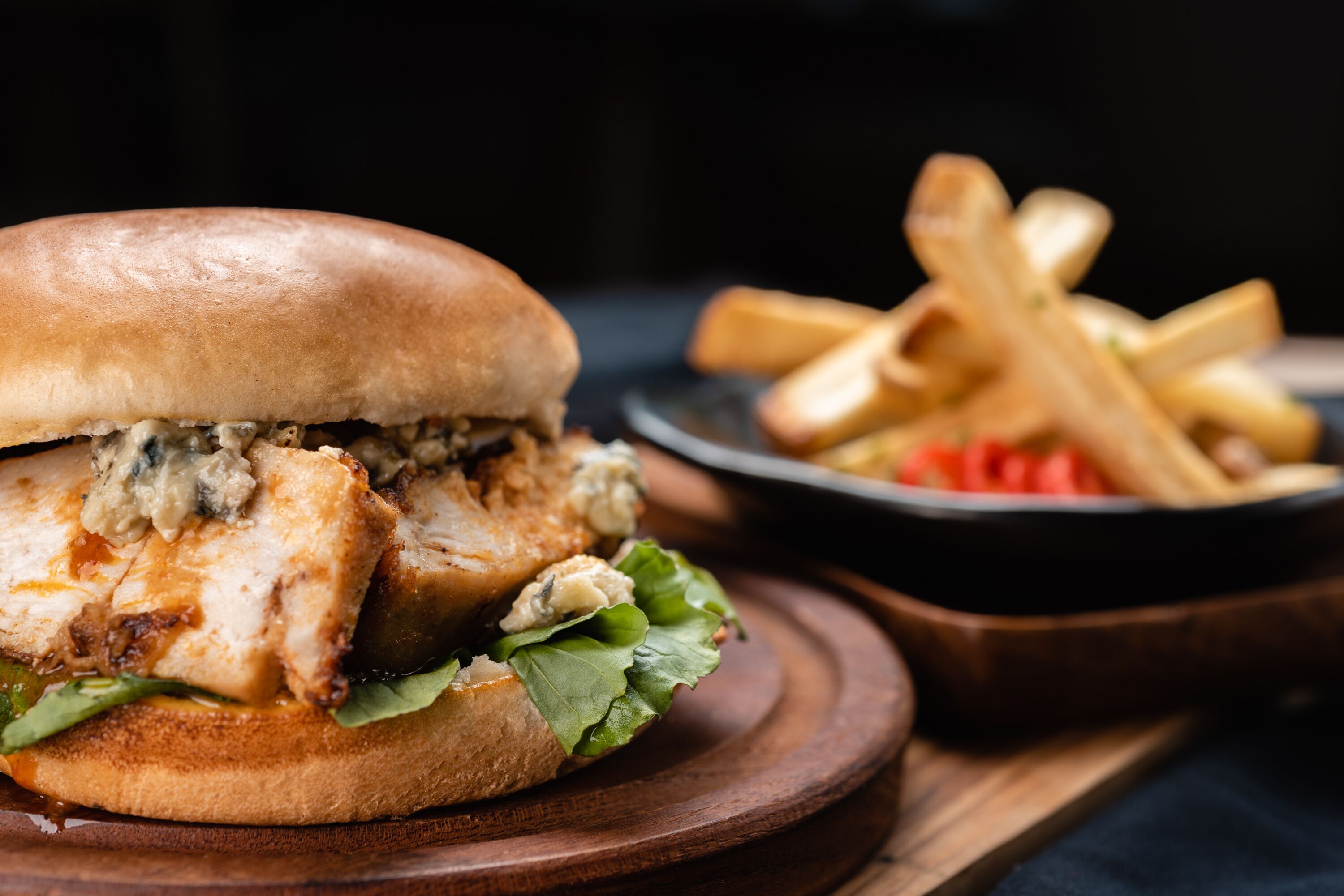 A sandwich with a bun, lettuce, and a creamy sauce, accompanied by a side of fries.