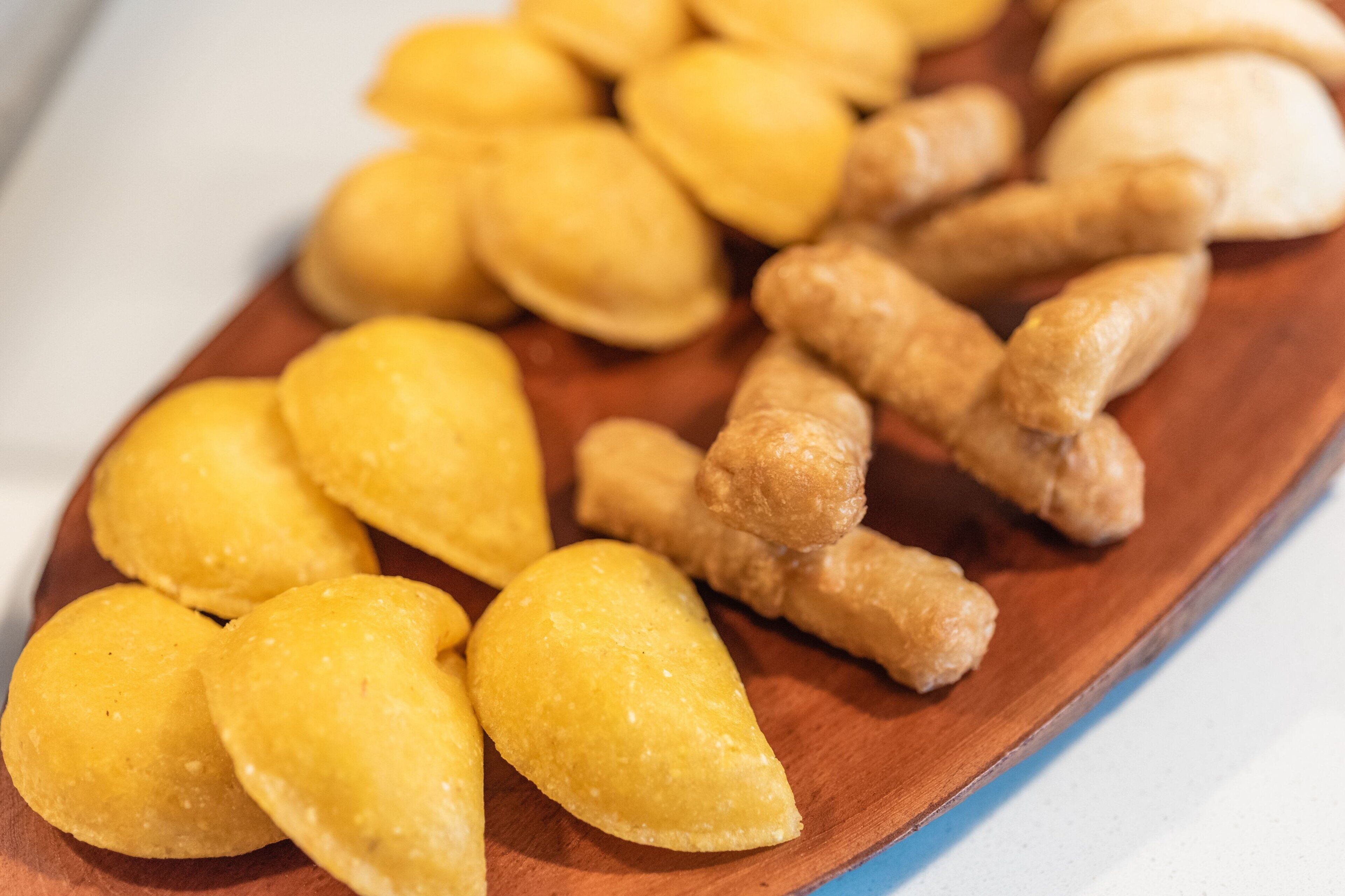 A wooden board with various pastries, including yellow and brown items.