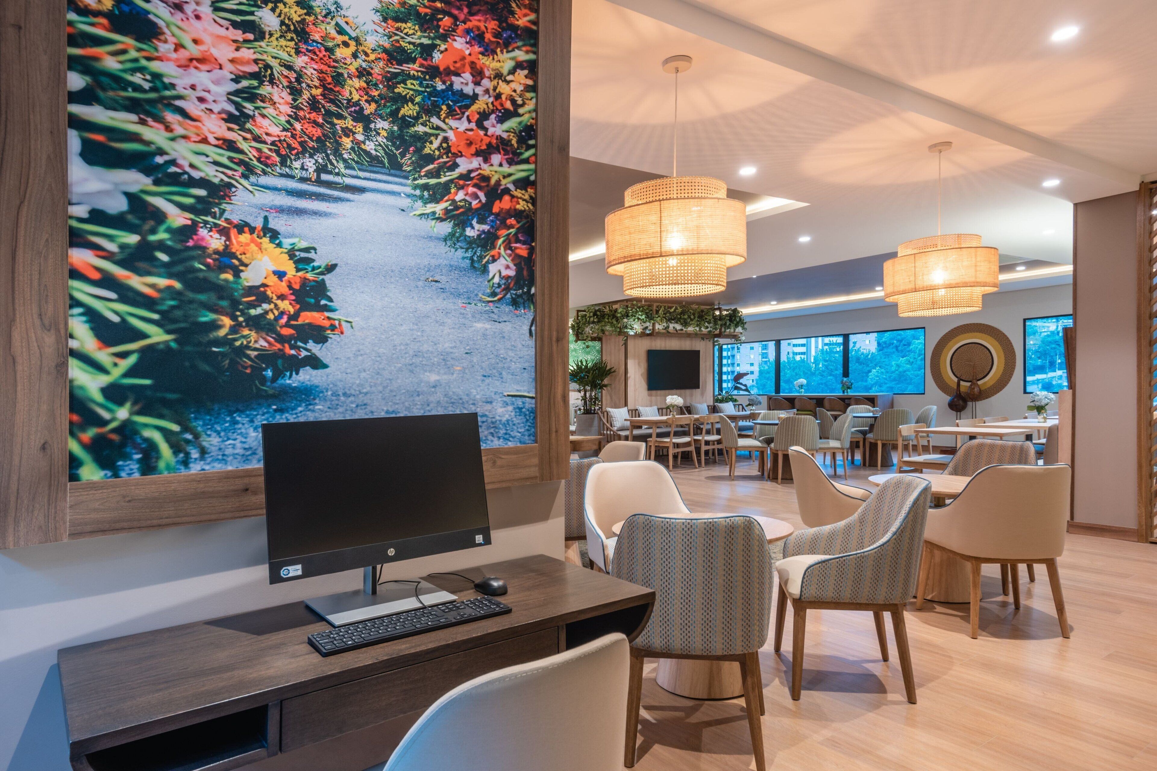 Un moderno hall de hotel con un gran mural floral, asientos cómodos y una pantalla de televisión grande.