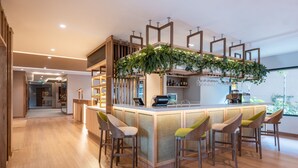 A modern kitchen with a central island, bar stools, and a hanging plant. - Fairfield by Marriott Medellin Sabaneta (Sabaneta)