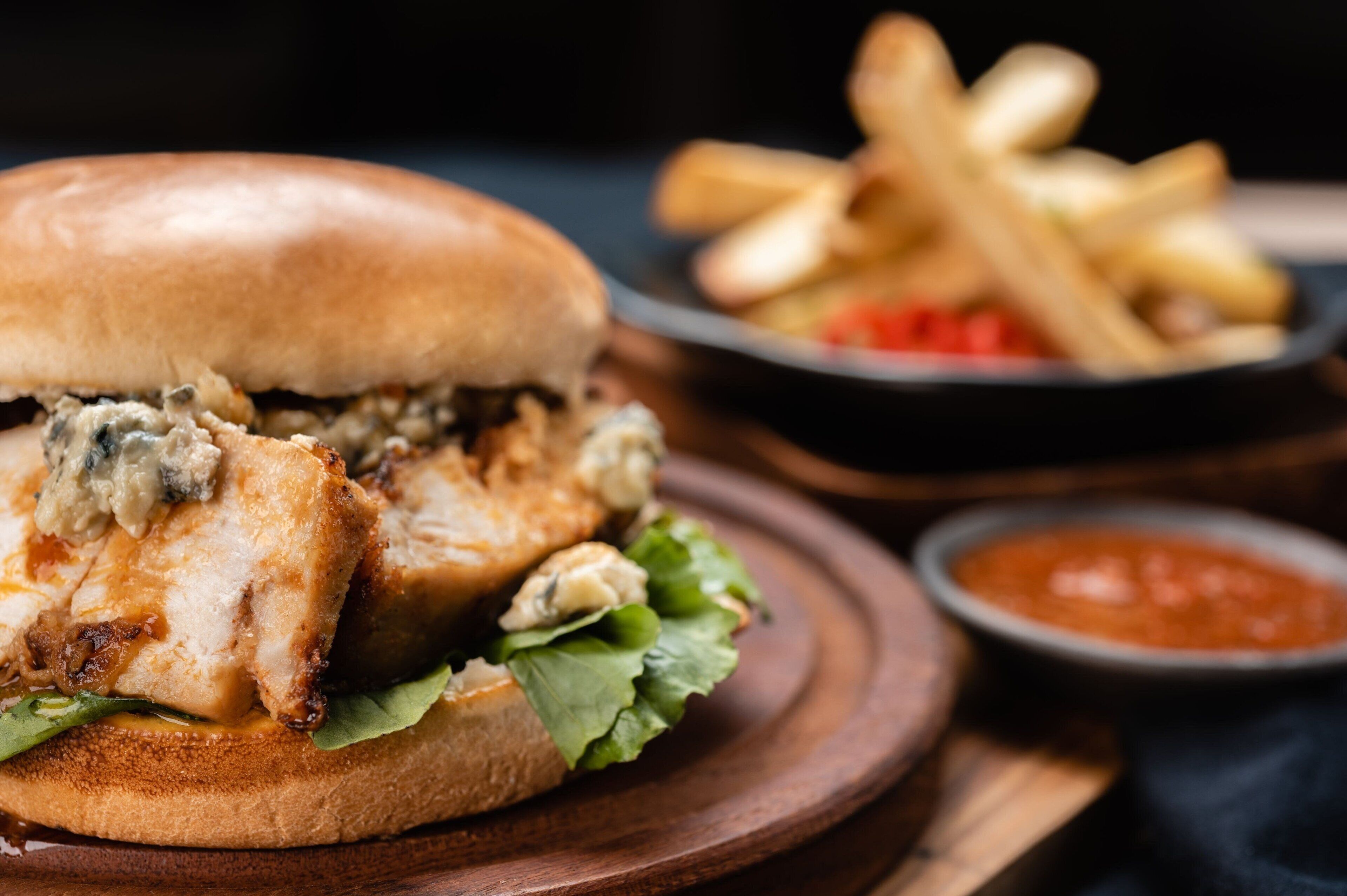 Un sándwich de pollo a la plancha con papas fritas y una salsa adicional.