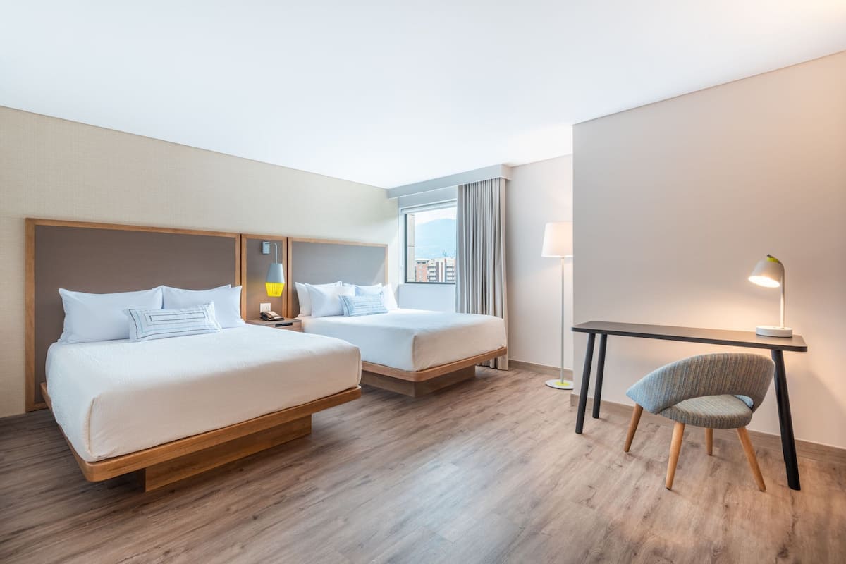 Ein Hotelzimmer mit zwei Betten, einem Schreibtisch und einem Sessel.