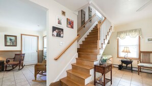 Un escalier avec des marches en bois et une rampe en bois, menant à un palier où se trouvent un banc et une petite table.