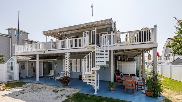 Une maison à deux étages dotée d’un patio couvert, d’un escalier en colimaçon et d’une terrasse.