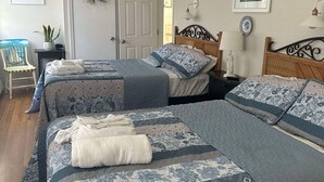 Une chambre avec deux lits, un ventilateur de plafond et une porte.