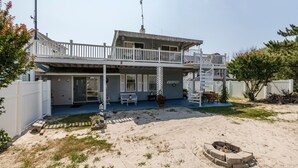 Une maison à deux étages avec un balcon, un foyer extérieur et une cour clôturée.