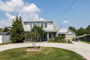 Ein zweistöckiges Haus mit Veranda, Garage und Auffahrt.