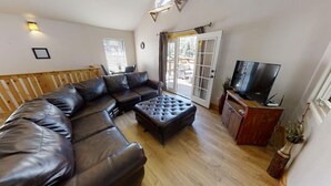 A living room with a sectional sofa, a coffee table, a television, and a sliding glass door leading to an outdoor area.