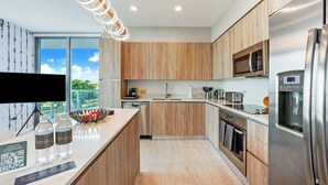 Eine moderne Küche mit Holzschränken, Edelstahlgeräten und einem großen Fenster mit Blick ins Freie.