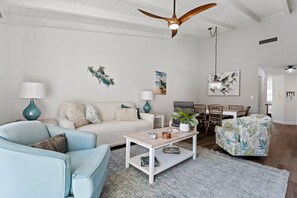 Una sala moderna con sofá, sillón, mesa de centro y comedor.