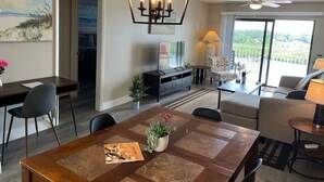 Un salon spacieux comprenant un coin repas, un ventilateur de plafond et une vue sur l’extérieur.