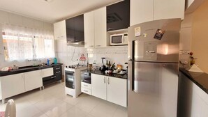 Una cocina moderna con armarios blancos, un refrigerador de acero inoxidable, un microondas y una estufa a gas.