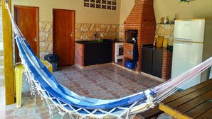 Una cocina con horno de ladrillo, refrigerador y una hamaca.