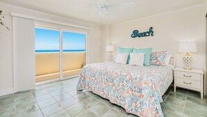 Une chambre avec un lit, des tables de chevet, un ventilateur de plafond et une vue sur la plage.