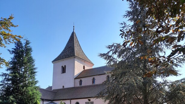 Une église dotée d’un clocher imposant et d’une cour dallée.