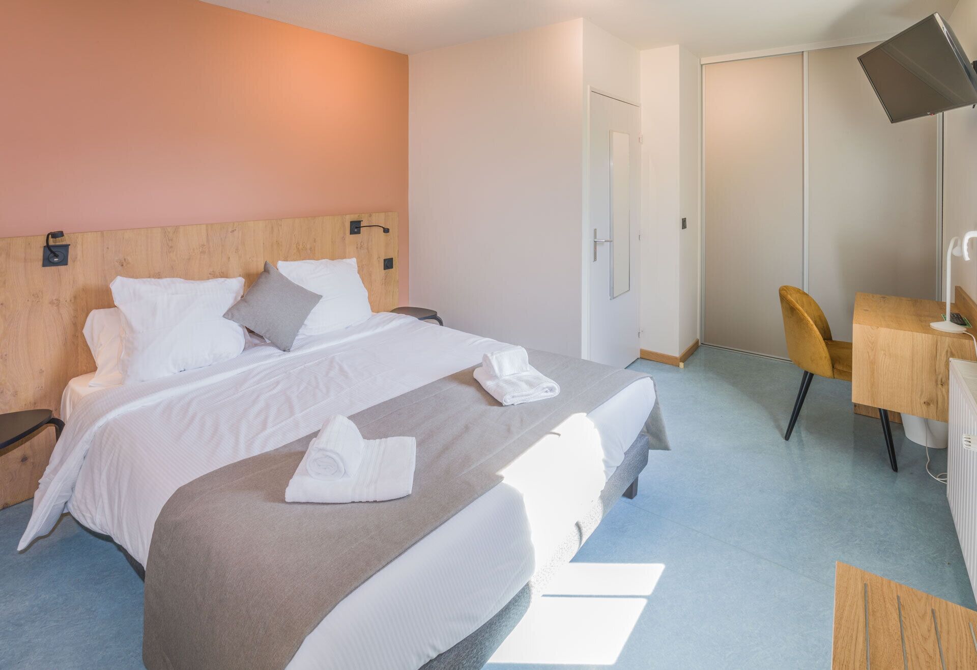 Une chambre d’hôtel avec deux lits, un bureau, une chaise et un téléviseur.