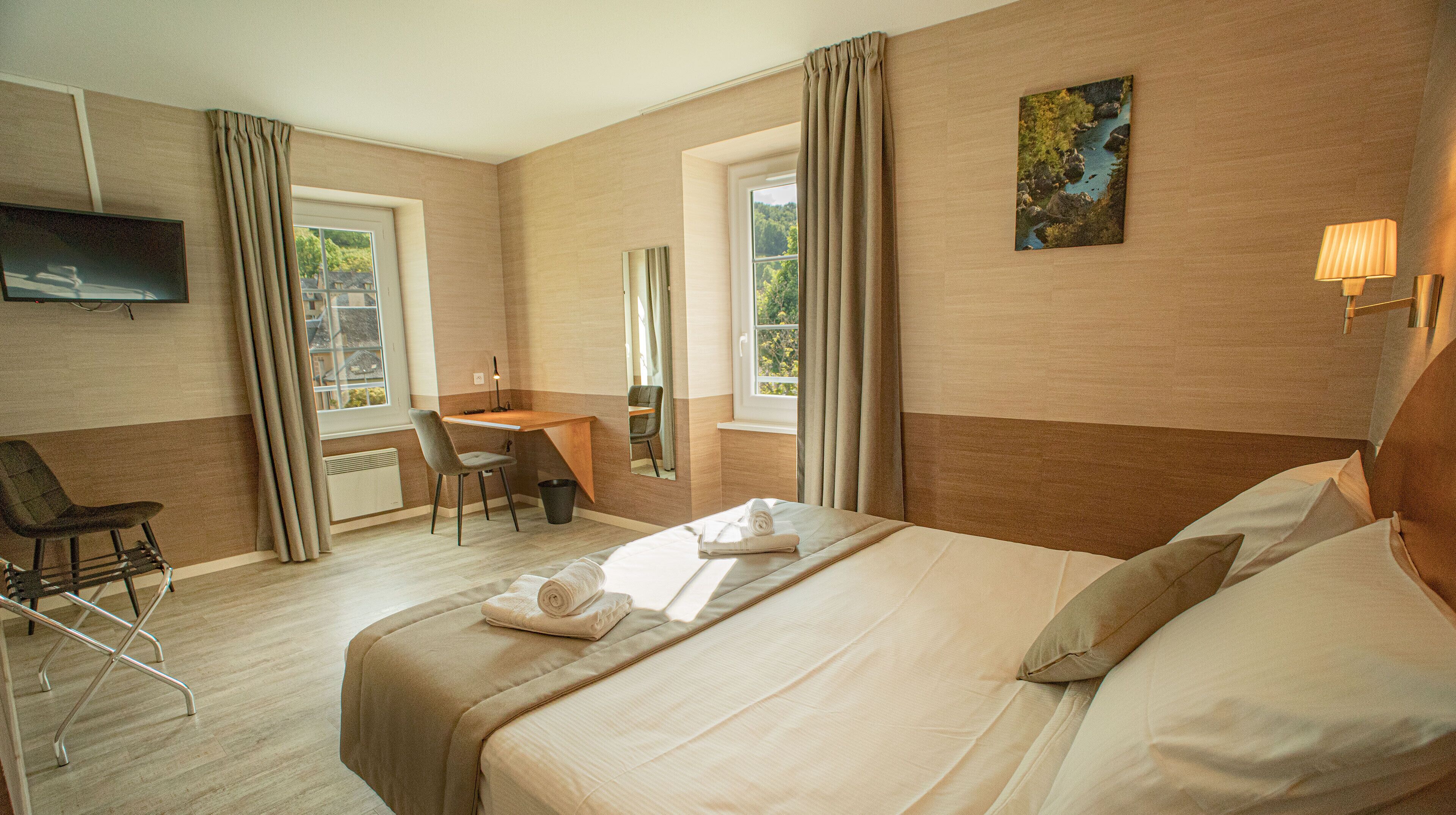 Una habitación de hotel con una cama, un escritorio, una silla y un televisor.