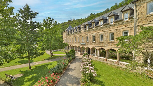 A large stone building with multiple windows and a central courtyard. - LOGIS HOTEL - L'HÔTEL DES BAINS (Salles-la-Source)
