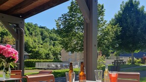 An outdoor patio with metal chairs and tables, bottles of beer, and glasses. - LOGIS HOTEL - L'HÔTEL DES BAINS (Salles-la-Source)