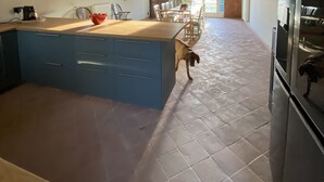 Eine geräumige Küche mit einer großen Kochinsel, Holzbalken an der Decke und einem gefliesten Boden.