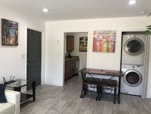 Un ambiente compatto con un tavolo da pranzo, due sedie, una lavatrice e opere d'arte alle pareti.