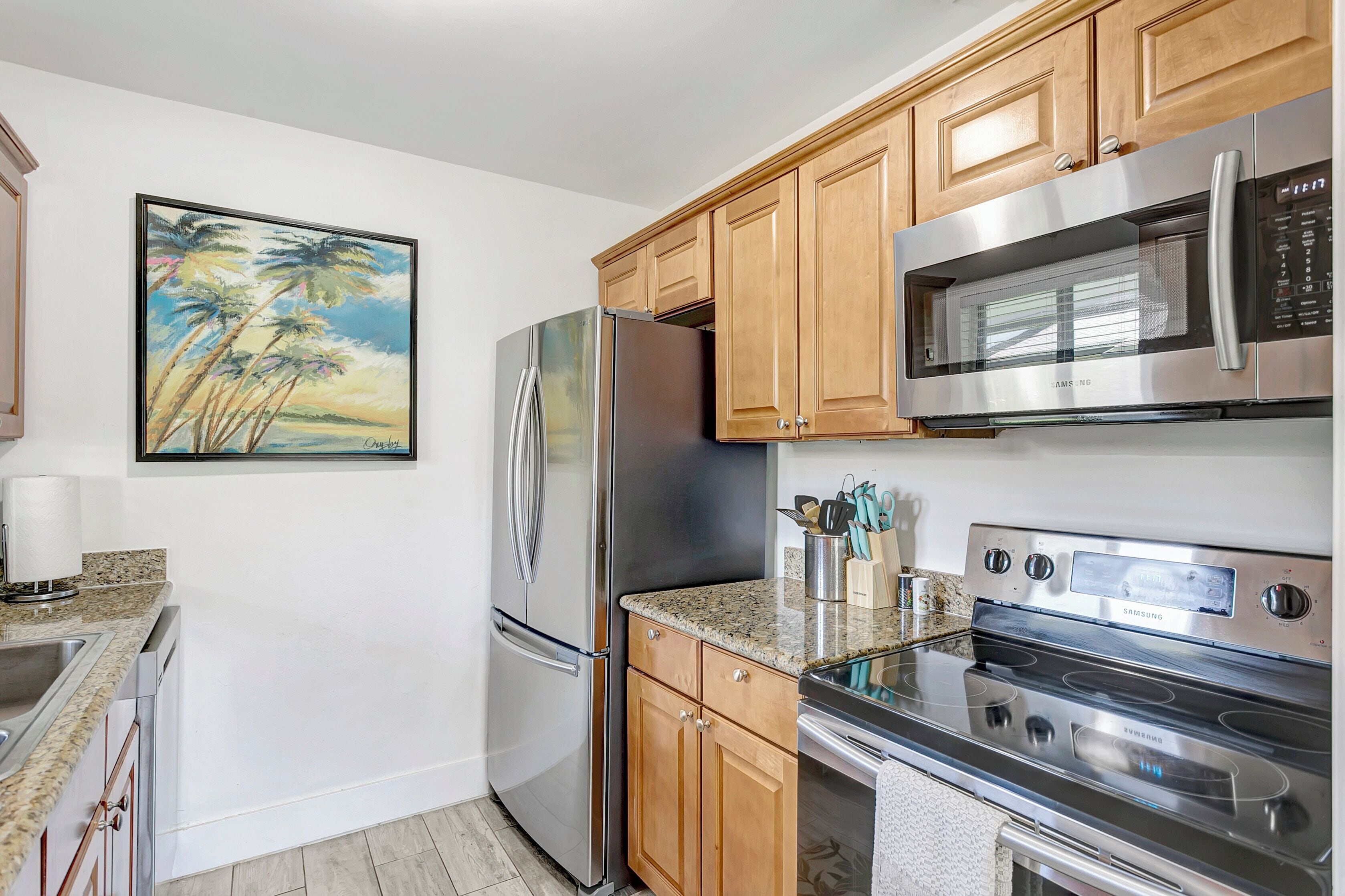 A modern kitchen with stainless steel appliances, wooden cabinets, and a granite countertop.