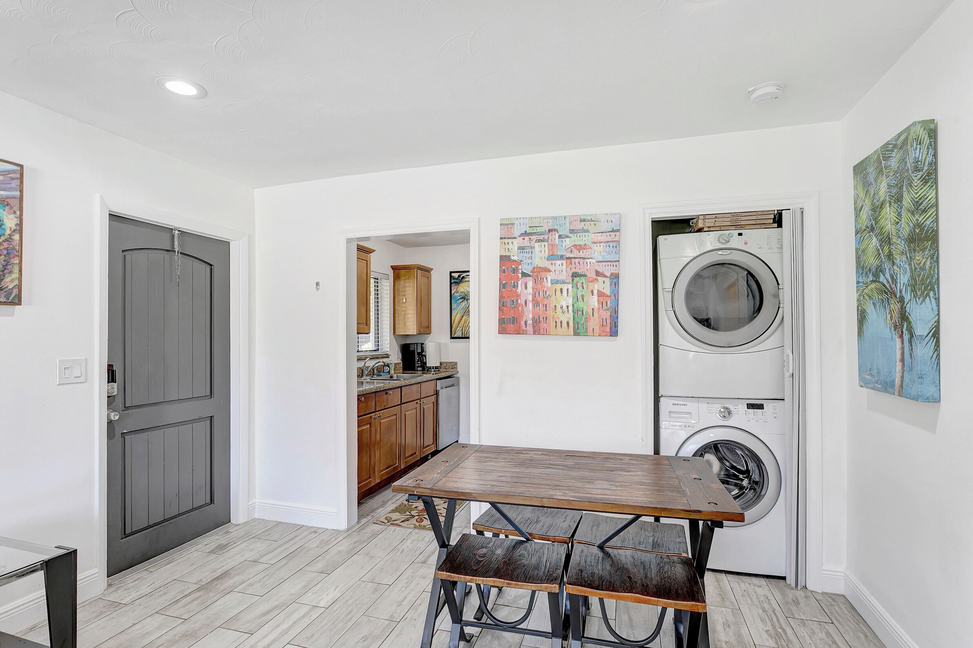 A laundry room with a washing machine, a table with benches, and a door leading to another room.