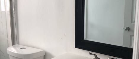 A bathroom with a white sink, a mirror, and a toilet.