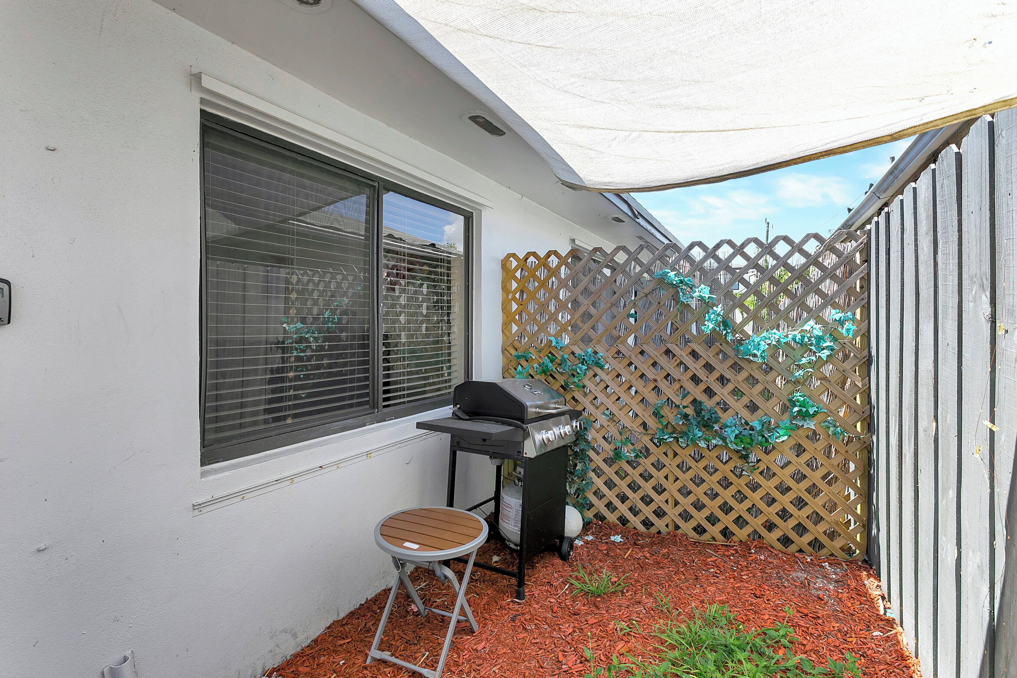 Un patio con una parrilla, una silla plegable y una valla de madera.