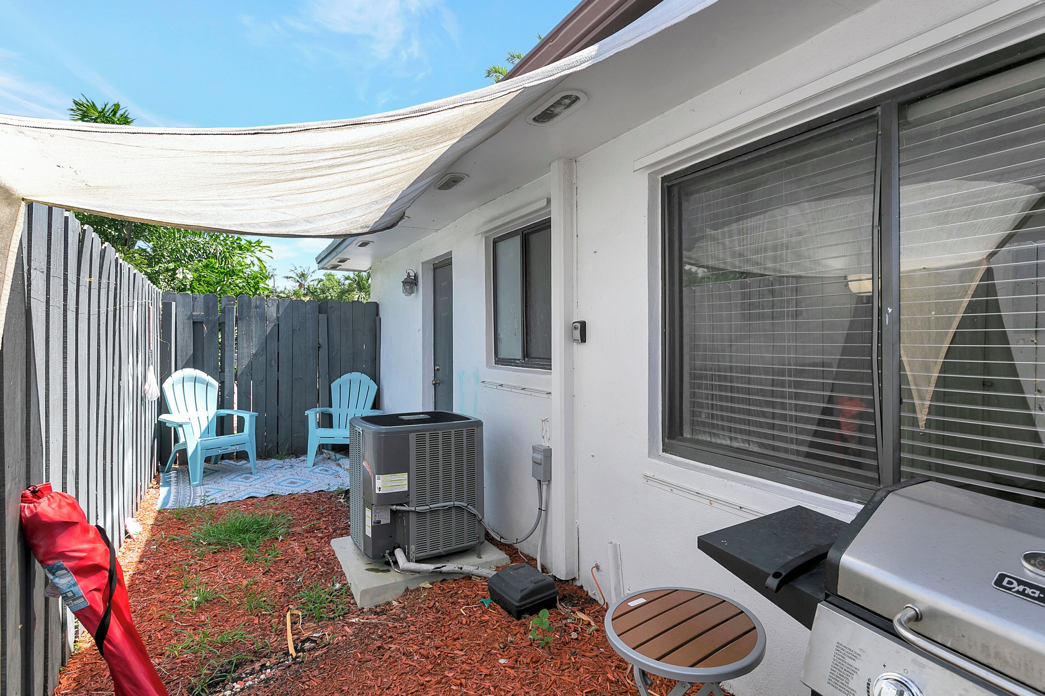 Un jardin avec un espace patio, du mobilier d’extérieur, un barbecue et un appareil de climatisation.