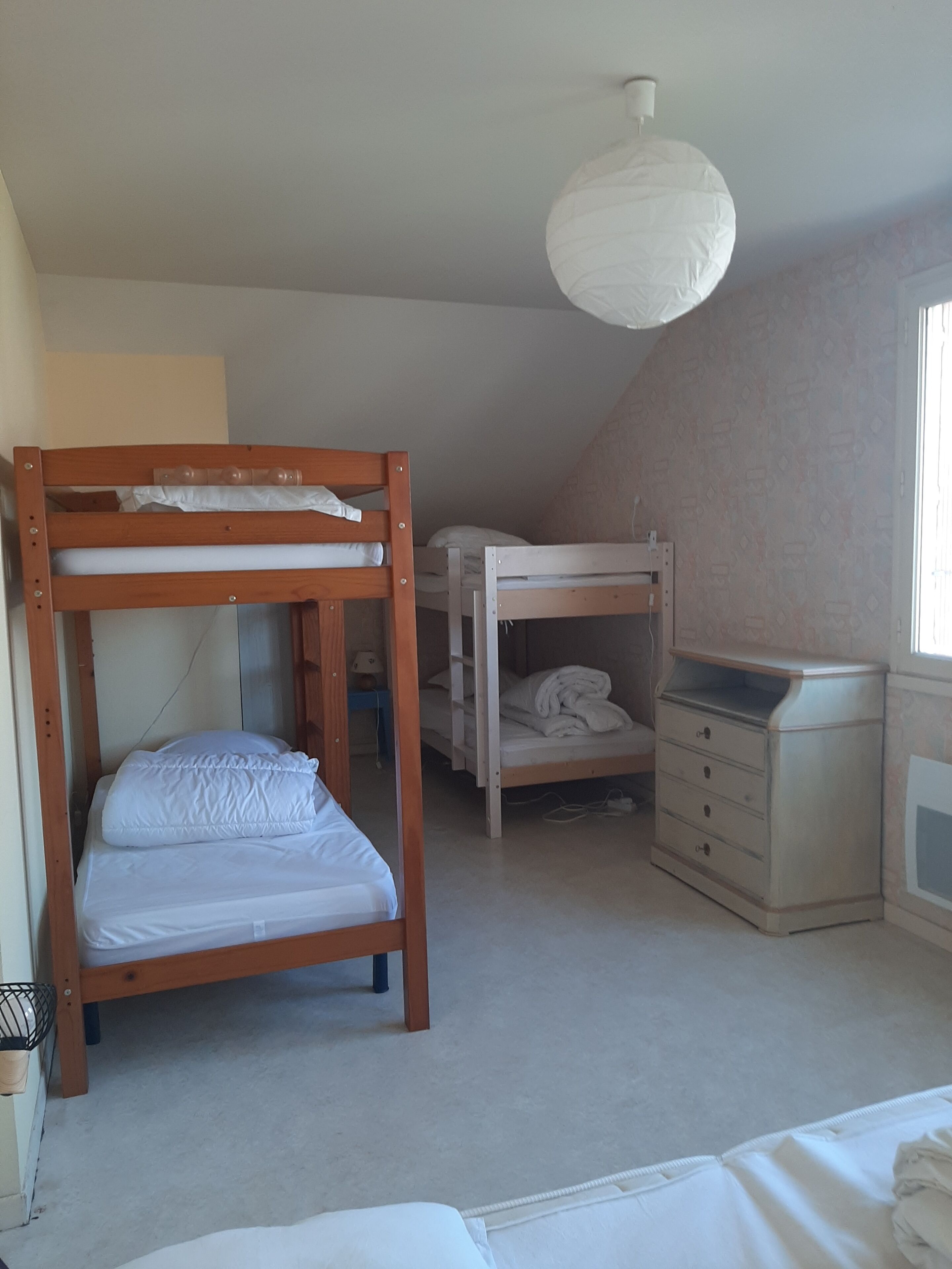 A dormitory room with bunk beds, a dresser, and a ceiling light.