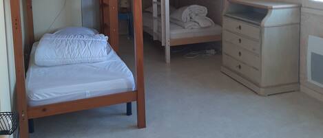 A dormitory room with bunk beds, a dresser, and a ceiling light.