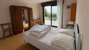 A bedroom with a bed, a wooden wardrobe, a desk, and a chair.