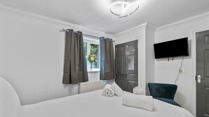 A hotel room with a bed, a chair, a TV, and a window with curtains. - Harmony Court by Pureserviced (Plymouth)
