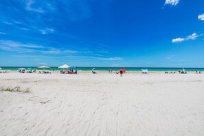 A wide sandy beach with clear blue skies and calm ocean.